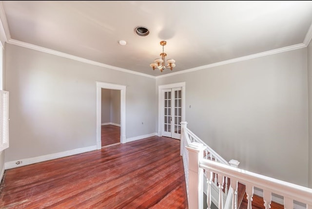 empty room featuring french doors, ornamental molding, hardwood / wood-style flooring, and an inviting chandelier