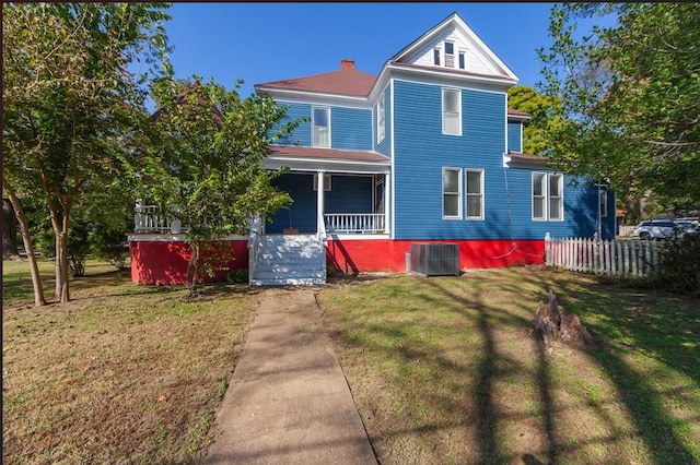 view of front of home featuring cooling unit, a front yard, and covered porch