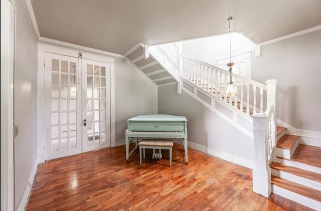 stairs with ornamental molding, hardwood / wood-style flooring, and french doors