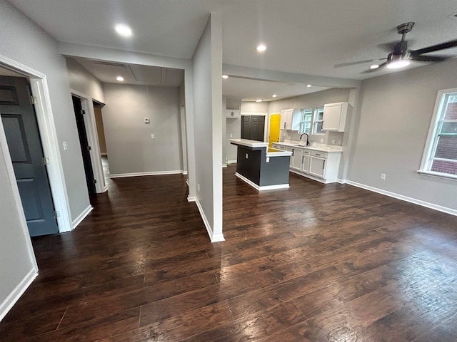 kitchen featuring a center island, sink, dark hardwood / wood-style flooring, white cabinetry, and a kitchen bar