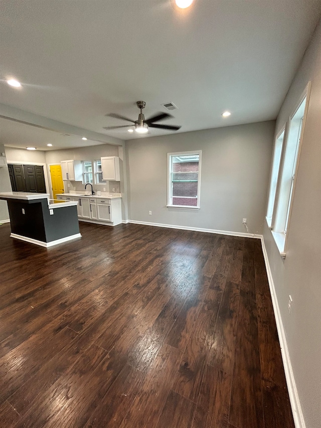 unfurnished living room with dark wood-type flooring, sink, and ceiling fan