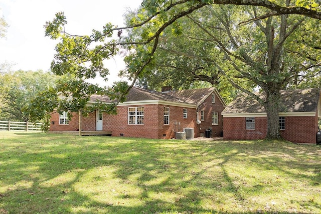 back of house with cooling unit and a lawn