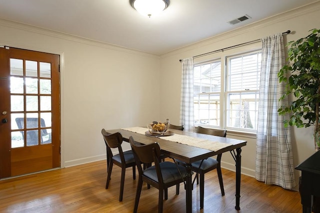 dining area with wood-type flooring and crown molding