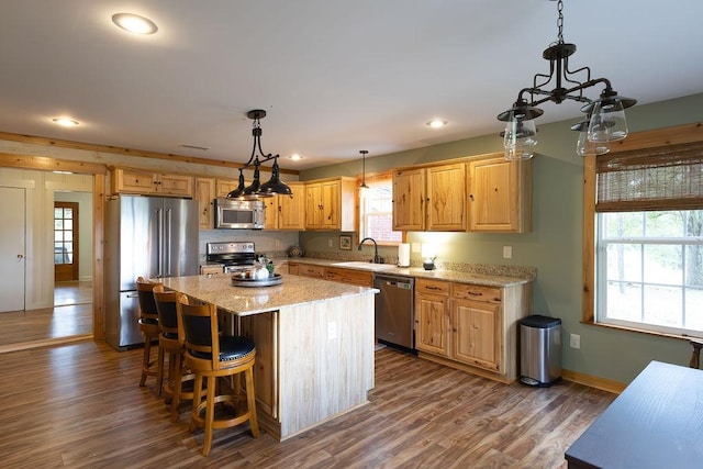 kitchen with dark hardwood / wood-style flooring, sink, hanging light fixtures, appliances with stainless steel finishes, and a center island