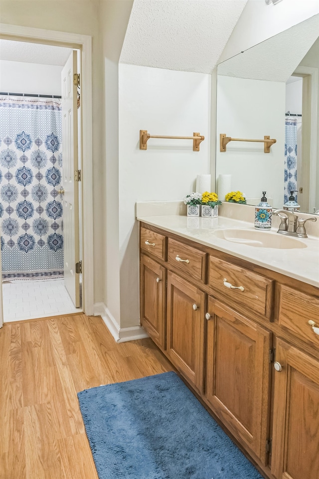 bathroom with a shower with curtain, vanity, wood-type flooring, and a textured ceiling