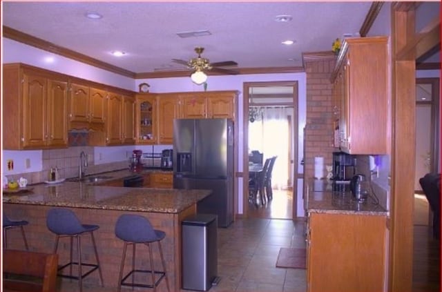 kitchen with crown molding, sink, ceiling fan, stainless steel fridge, and kitchen peninsula