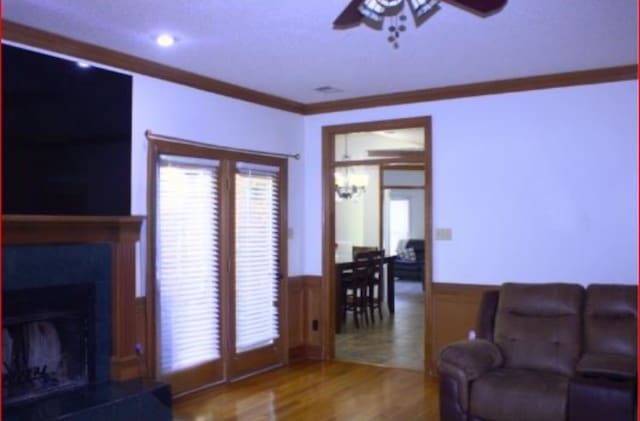 living room featuring hardwood / wood-style flooring, ceiling fan, and ornamental molding