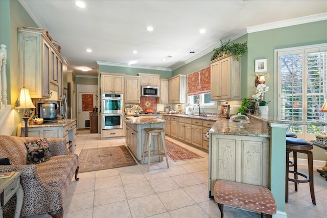 kitchen with appliances with stainless steel finishes, crown molding, a kitchen bar, and a center island