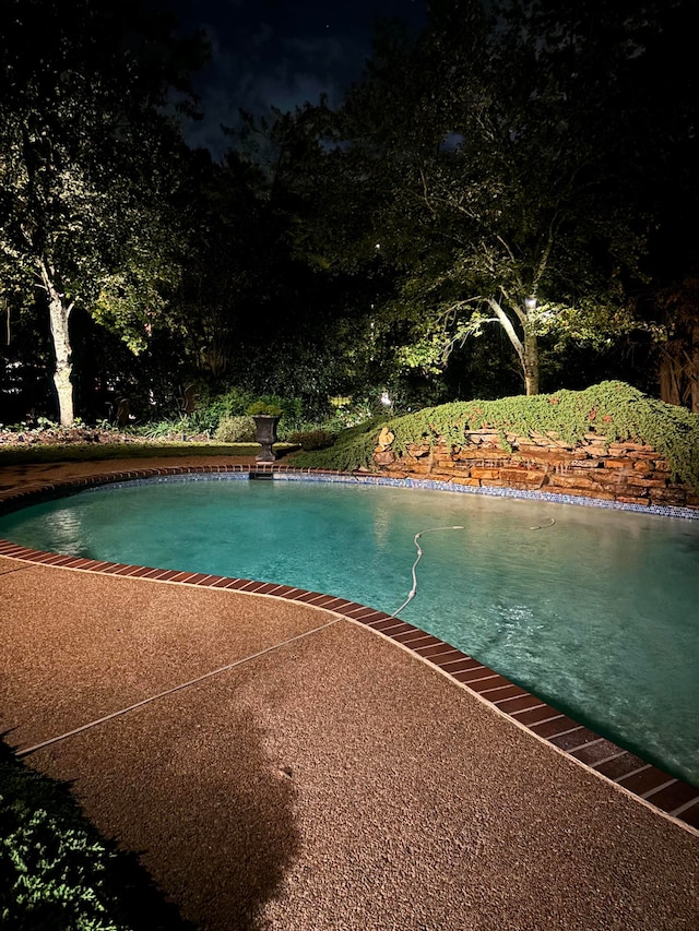 pool at twilight featuring a patio area