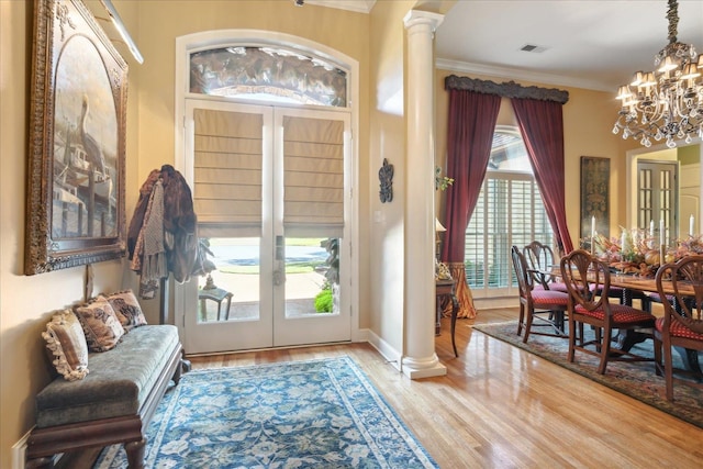 foyer entrance with ornamental molding, a healthy amount of sunlight, an inviting chandelier, and light hardwood / wood-style flooring