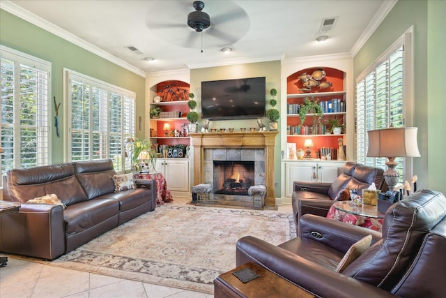 tiled living room featuring ceiling fan, a tile fireplace, ornamental molding, and a healthy amount of sunlight