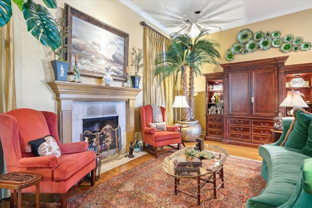 living area with crown molding, a tiled fireplace, and light hardwood / wood-style floors