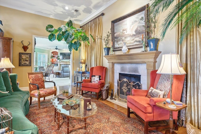 living area with wood-type flooring, crown molding, and ceiling fan