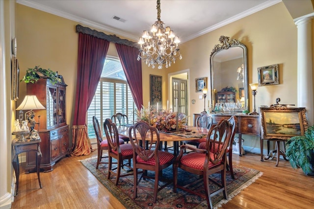 dining area featuring light wood-type flooring, decorative columns, ornamental molding, and a chandelier