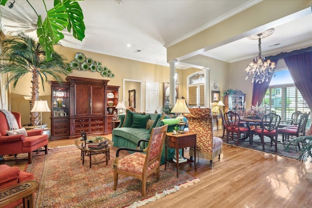 living room with ornamental molding, light wood-type flooring, decorative columns, and a chandelier