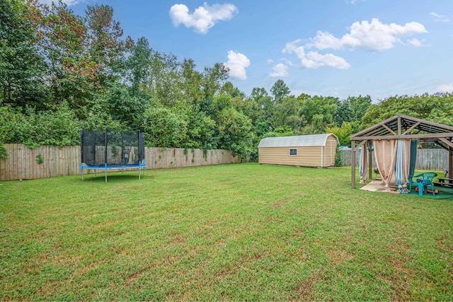 view of yard featuring a trampoline, a gazebo, a patio, and a storage unit