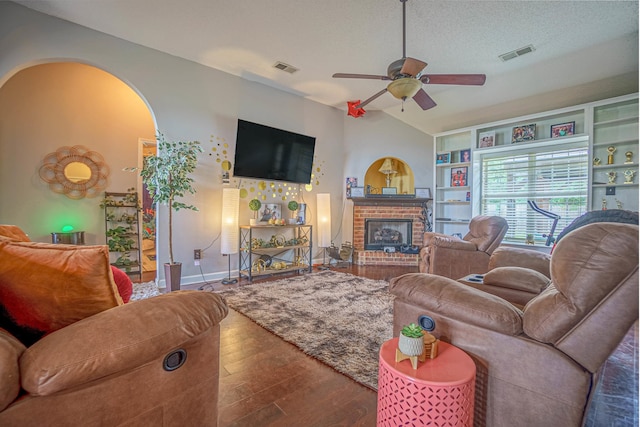 living room featuring ceiling fan, a textured ceiling, dark wood-type flooring, a fireplace, and vaulted ceiling