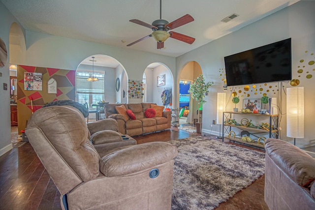 living room with ceiling fan with notable chandelier and dark hardwood / wood-style floors