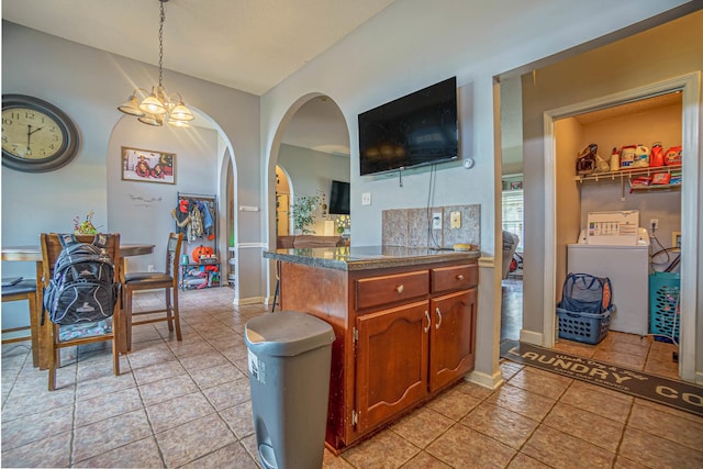 kitchen featuring an inviting chandelier, hanging light fixtures, light tile patterned floors, and washer / dryer