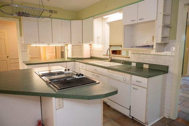 kitchen featuring dark tile patterned floors, sink, white dishwasher, decorative backsplash, and white cabinets