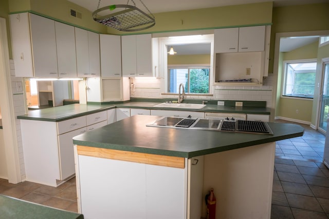 kitchen featuring tasteful backsplash, a kitchen island, sink, and white cabinetry