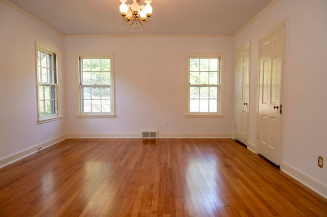 spare room with hardwood / wood-style flooring, crown molding, and a chandelier