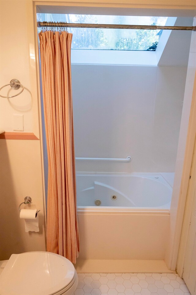 bathroom featuring a skylight, shower / bathtub combination with curtain, tile patterned floors, and toilet