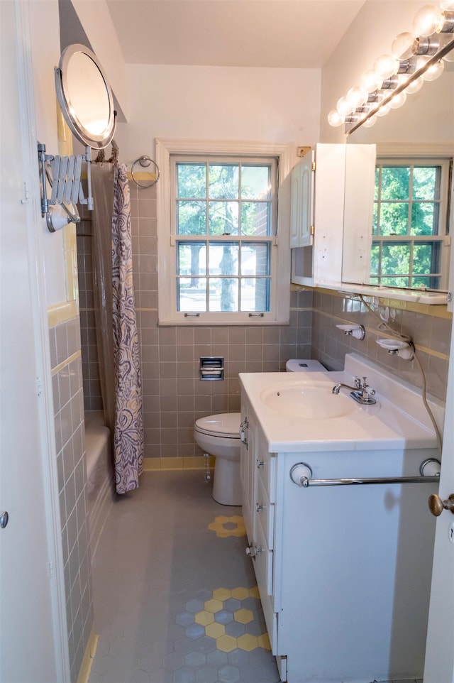 bathroom featuring tile patterned flooring, toilet, tile walls, and vanity