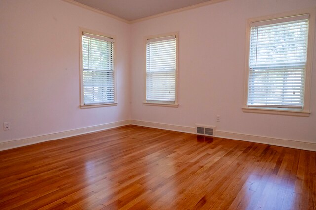 unfurnished room with crown molding, light wood-type flooring, and a healthy amount of sunlight