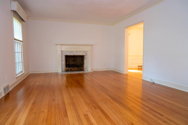 unfurnished living room featuring a premium fireplace, crown molding, and light hardwood / wood-style flooring