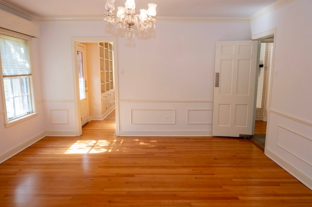 unfurnished room with a notable chandelier, crown molding, and light hardwood / wood-style flooring