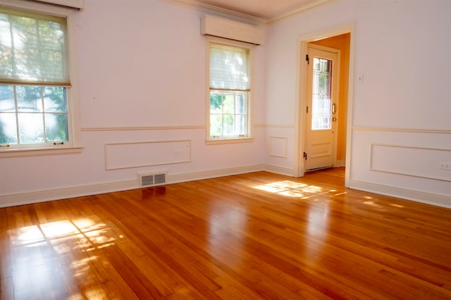 empty room with crown molding and light hardwood / wood-style flooring