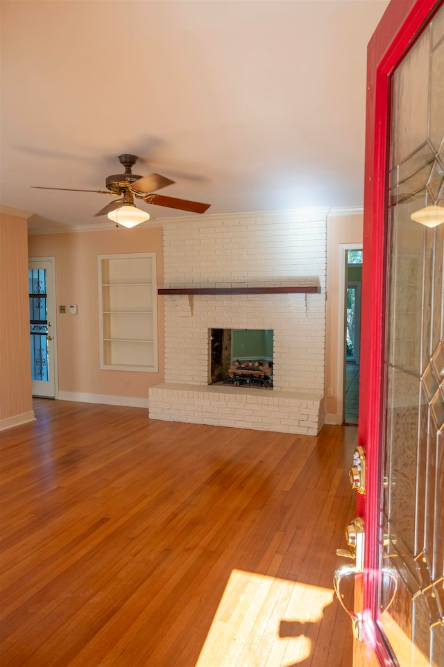 unfurnished living room with hardwood / wood-style flooring, a fireplace, ceiling fan, and built in shelves