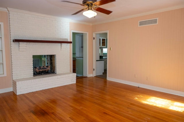 unfurnished living room with a brick fireplace, ornamental molding, hardwood / wood-style floors, and ceiling fan