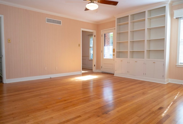 empty room with ornamental molding, ceiling fan, light hardwood / wood-style floors, and built in features