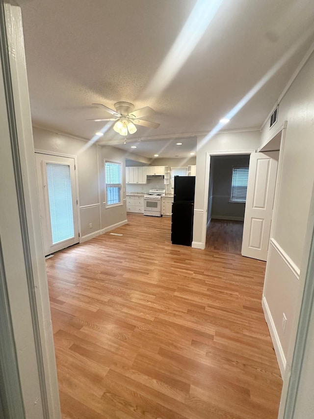 unfurnished living room featuring light hardwood / wood-style flooring, a textured ceiling, and ceiling fan