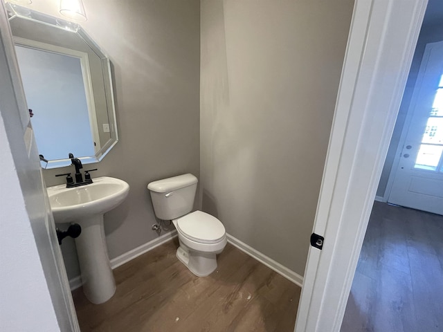 bathroom featuring a sink, wood finished floors, toilet, and baseboards