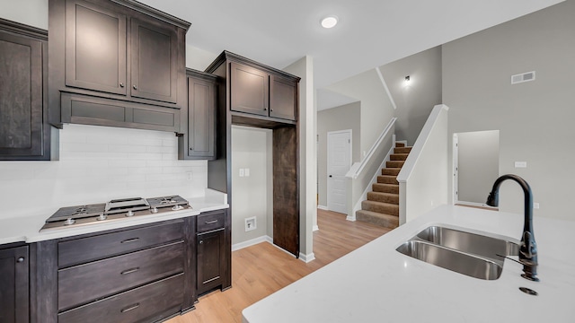 kitchen with stainless steel gas cooktop, light countertops, tasteful backsplash, and a sink