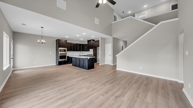 unfurnished living room featuring recessed lighting, ceiling fan with notable chandelier, visible vents, baseboards, and light wood finished floors