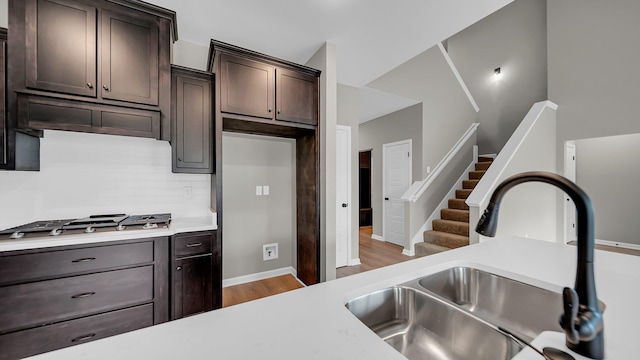 kitchen with stainless steel gas stovetop, light countertops, a sink, and decorative backsplash