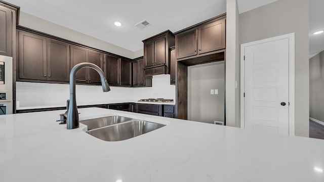 kitchen featuring stainless steel appliances, light countertops, visible vents, a sink, and dark brown cabinets