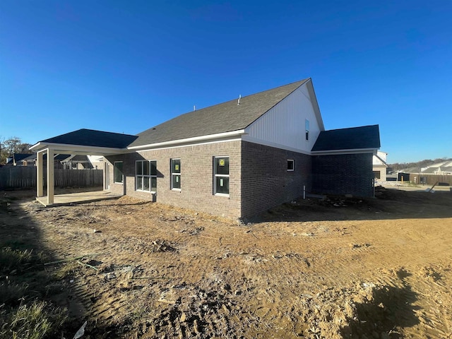 rear view of house with brick siding, fence, and a patio