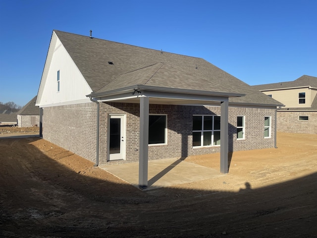 back of property with a patio area, a shingled roof, and brick siding