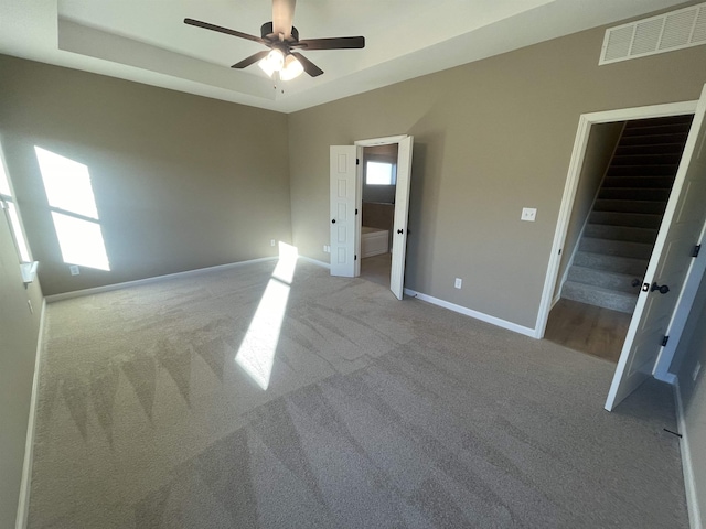 carpeted empty room with a tray ceiling and ceiling fan