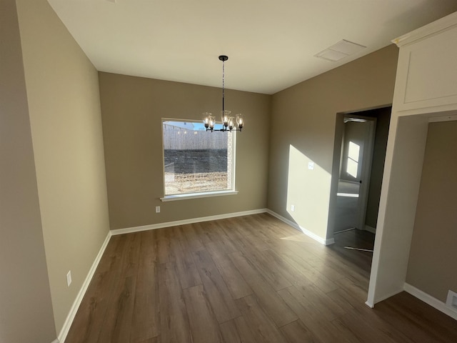 unfurnished dining area with an inviting chandelier and hardwood / wood-style flooring