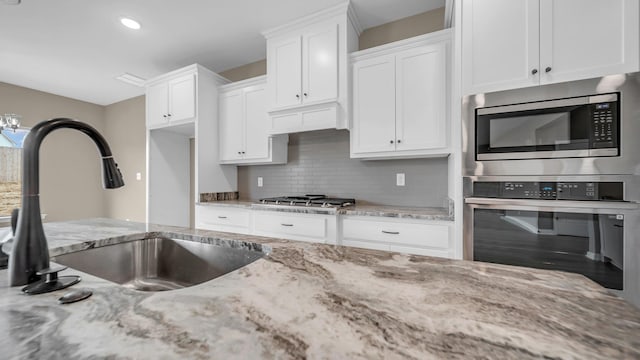 kitchen featuring white cabinetry, stainless steel appliances, sink, and light stone counters