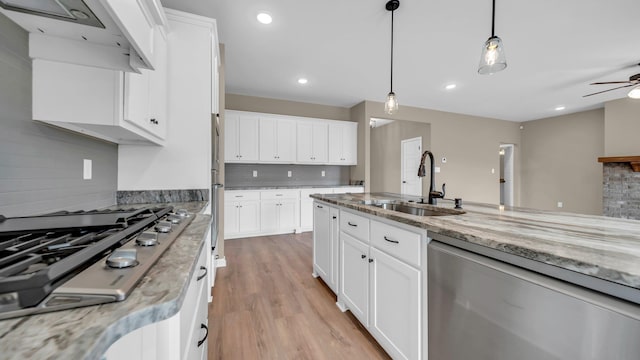 kitchen with stainless steel appliances, white cabinetry, sink, and decorative light fixtures