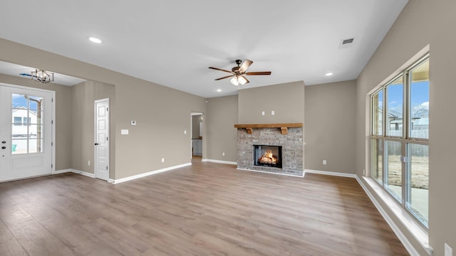 unfurnished living room featuring ceiling fan with notable chandelier and light hardwood / wood-style floors