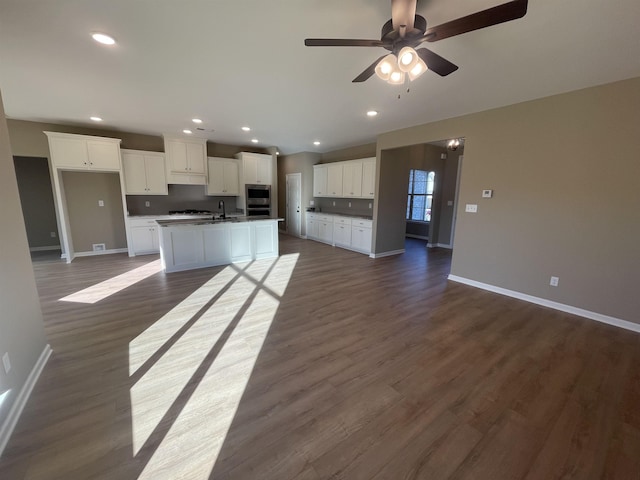 kitchen featuring sink, dark hardwood / wood-style floors, ceiling fan, a kitchen island with sink, and white cabinets