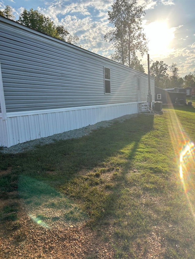 view of home's exterior with a lawn and central AC